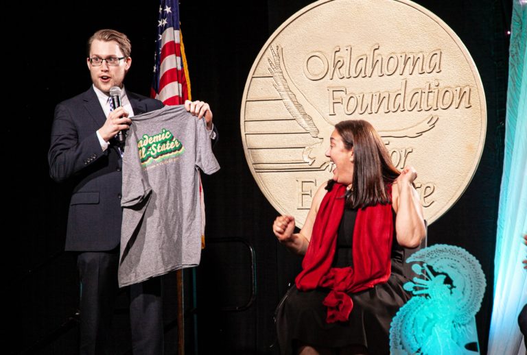 All-State Alumnus David Postic surprises Erin Gruwell with a 2021 Academic All-State T-shirt.